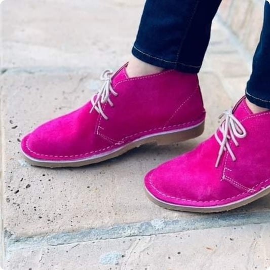 A photo of a woman's feet, showing off pink leather suede shoes. 